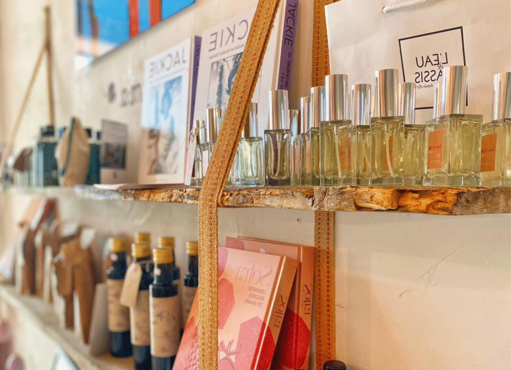 Étagère avec des cosmétiques naturels, des huiles et des livres d'épicerie fine bio dans la boutique Mademoiselle K à Cassis, concept store bohème chic.