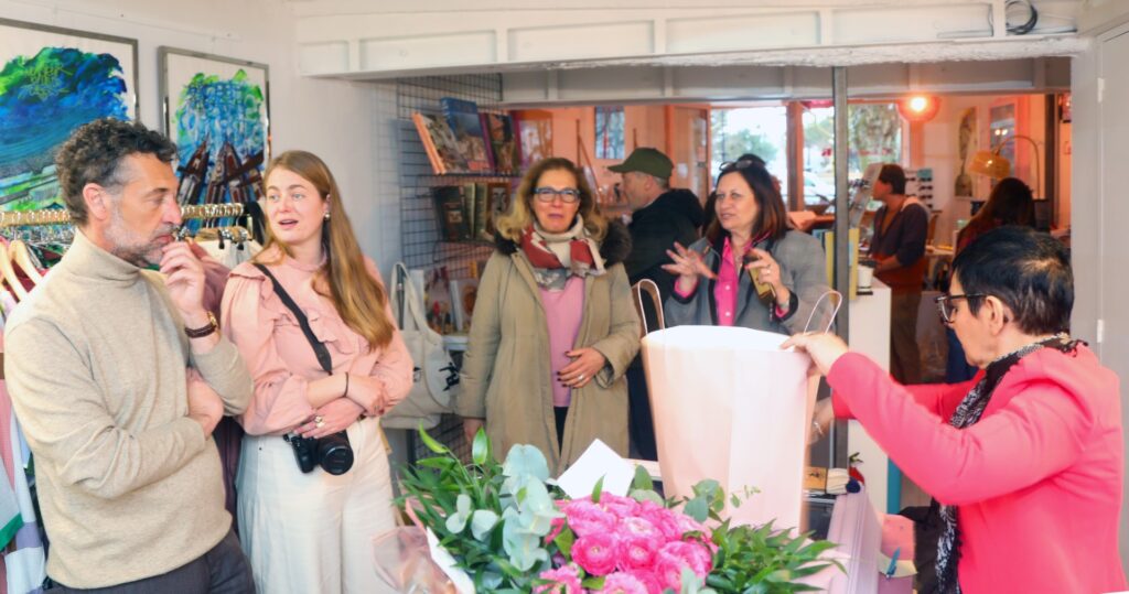 Moment de convivialité pendant l'inauguration de Mademoiselle K à Cassis, avec des invités discutant et appréciant l'ambiance chaleureuse de la boutique.