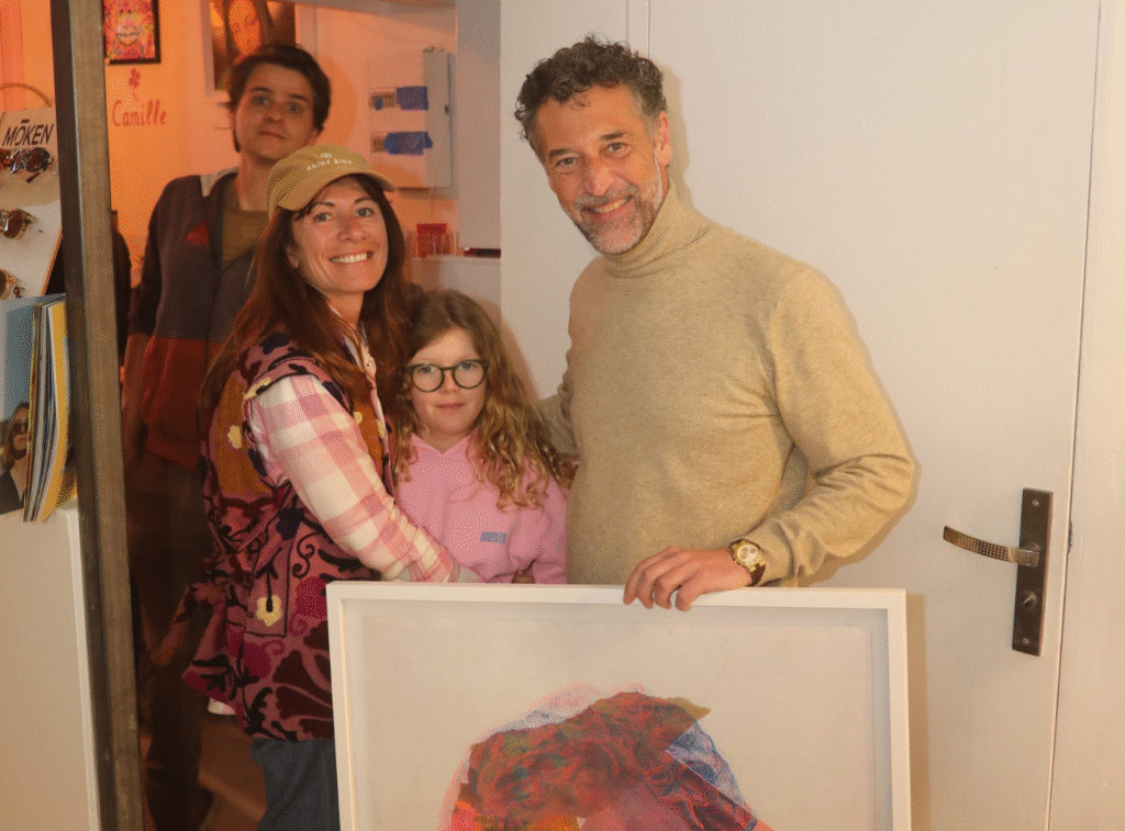 Moment convivial lors de l'inauguration de Mademoiselle K à Cassis, avec des invités posant pour une photo en tenant une œuvre d'art.